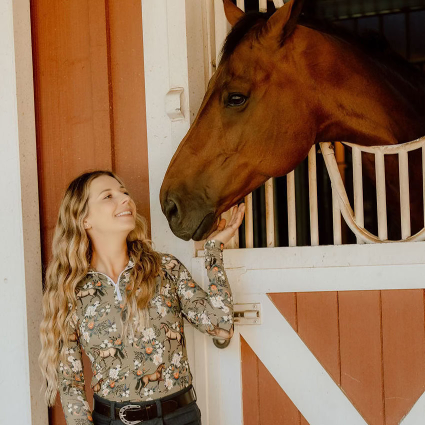 Woman petting a horse in front of a barn door