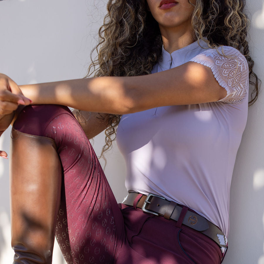 Woman sitting on a bench wearing a white top and burgundy breeches